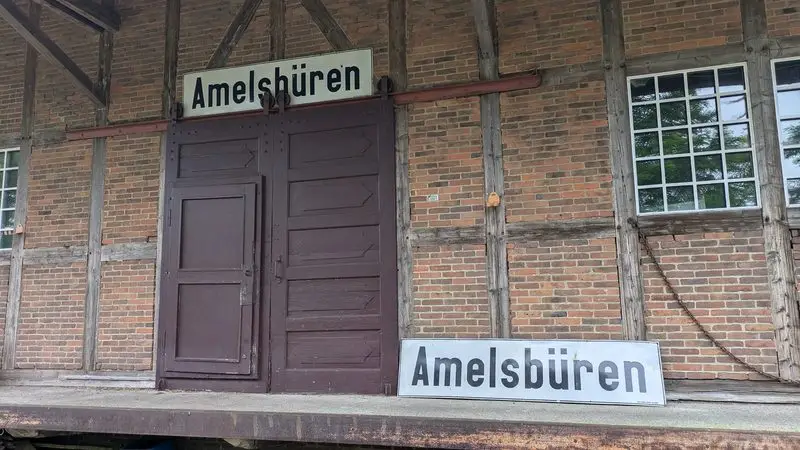 Panneaux de gare portant le nom Amelsbüren sur une façade en brique