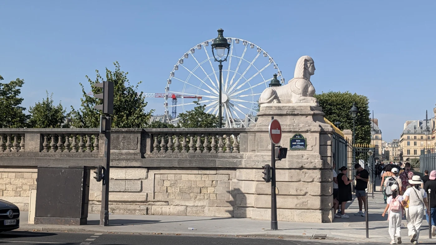 Vue d’ensemble de la sphinge Ouest à l’entrée Flore du jardin des Tuileries, avec son environnement visible autour.